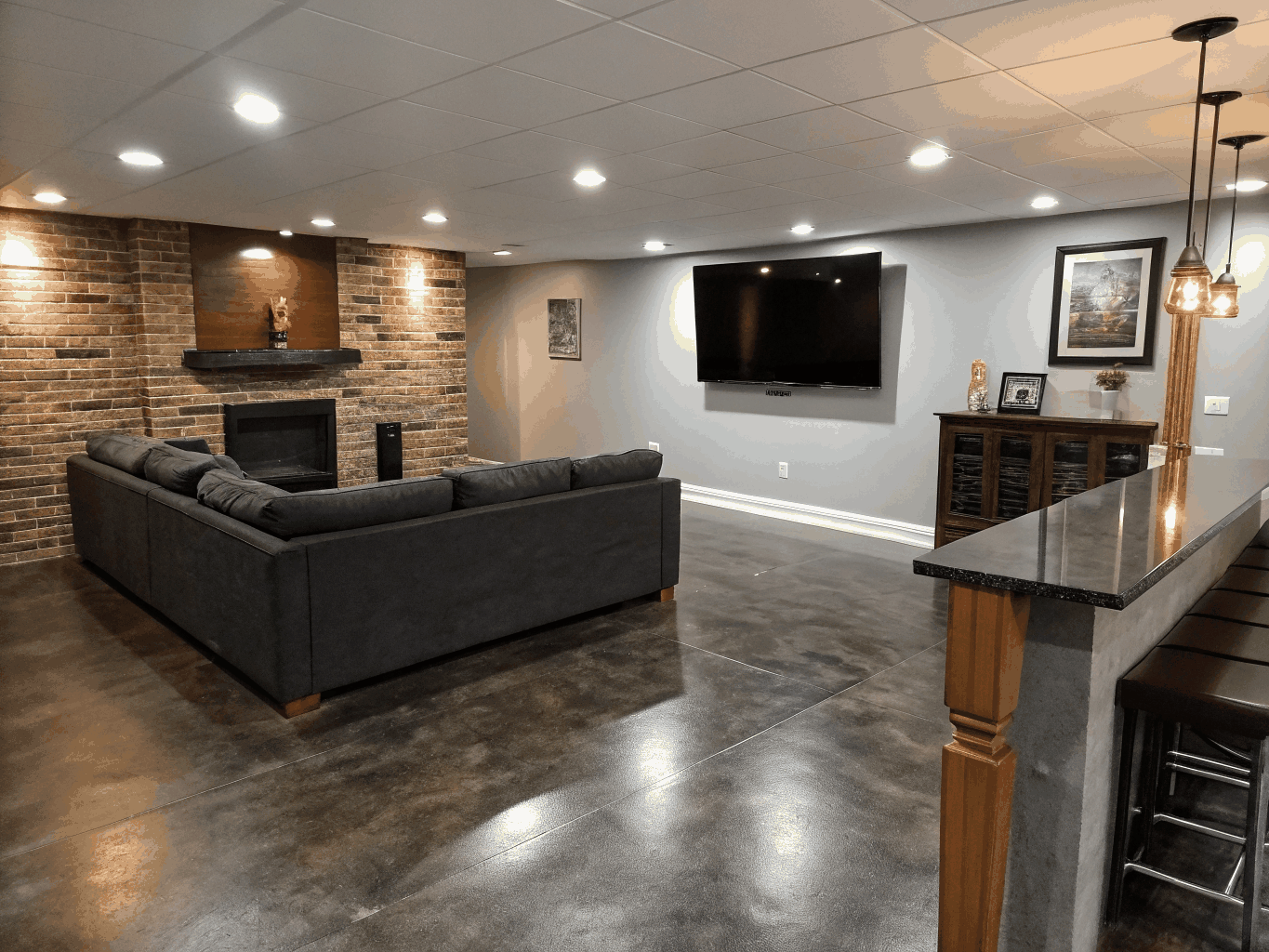 Modern finished basement lounge with built-in bar, recessed lighting, and entertainment seating