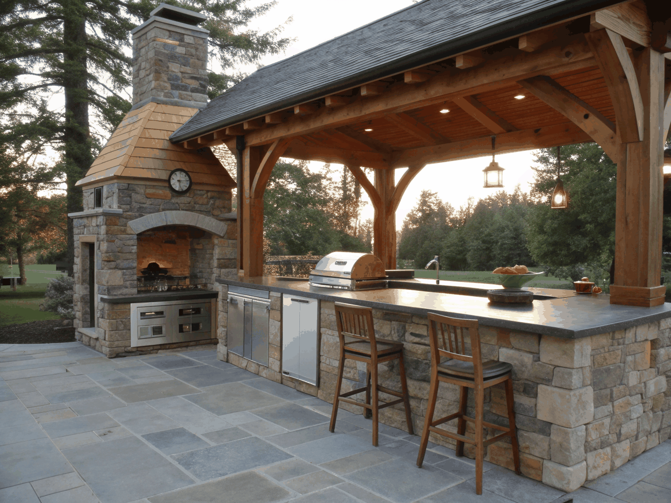 Custom cedar pavilion with stone fireplace and integrated outdoor kitchen in Brookhaven