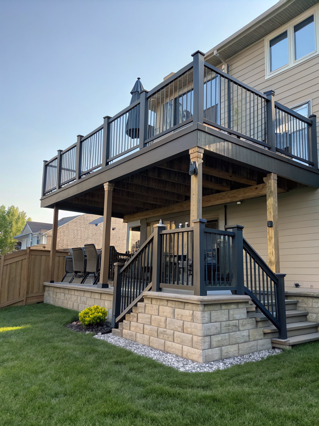 Modern elevated multi-level composite deck with black aluminum railings overlooking a Brookhaven wooded backyard