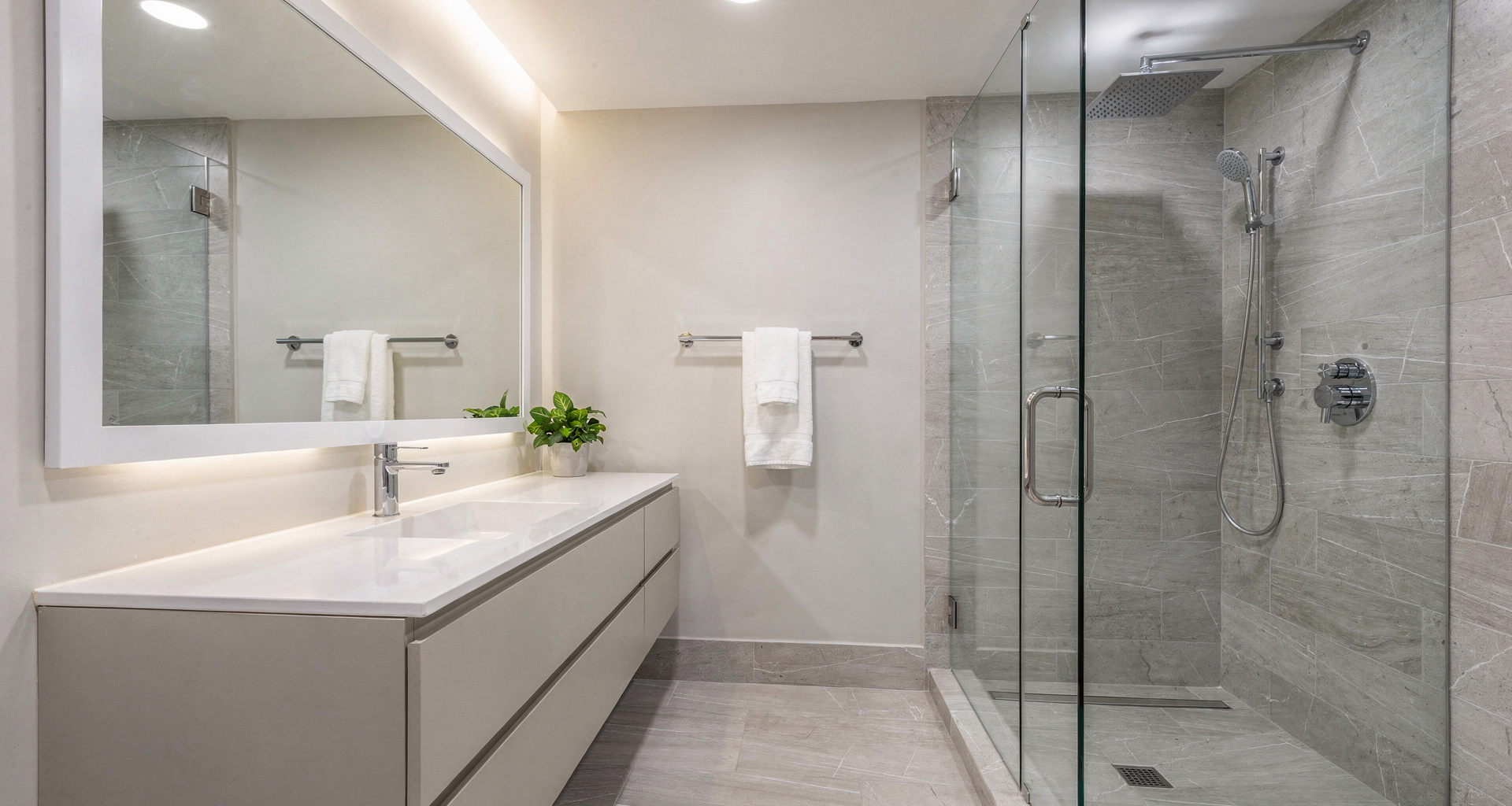 Custom frameless glass walk-in shower with natural stone tile and brass fixtures in Brookhaven home
