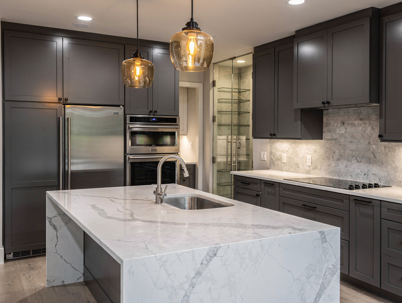 Modern architectural kitchen design concept with reeded glass upper cabinets and custom hood