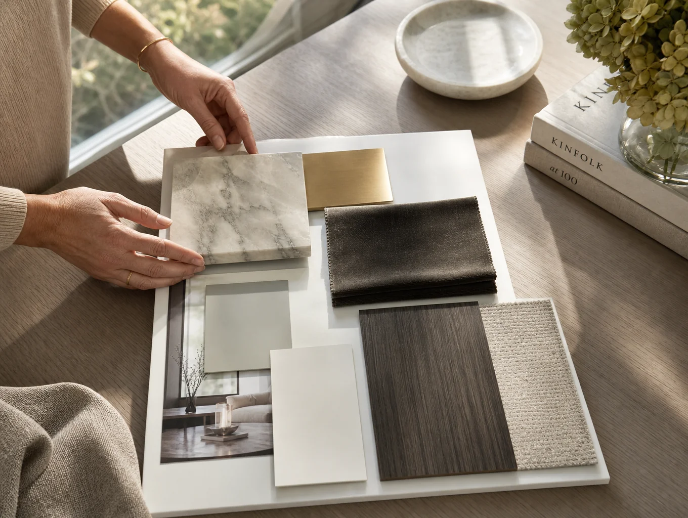 Interior design material board with marble samples, brass hardware, and architectural drawings